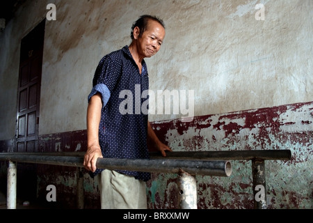 Un homme amputé exerce sur les barres parallèles au Centre national de réhabilitation à Vientiane au Laos. Banque D'Images