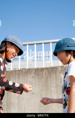 Garçon et fille jouer Pierre papier ciseaux Japon Banque D'Images