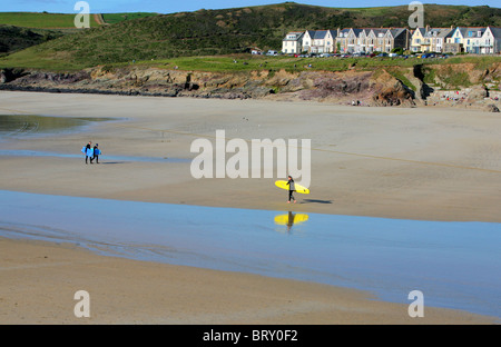 Les surfeurs sur la plage à marée basse à Polzeath, Cornwall, England, UK. Banque D'Images