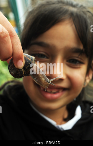 Les études d'un enfant un escargot soulevant, dans le cadre de l'expérience de jardinage en visite dans un centre spécial, Bradford Banque D'Images