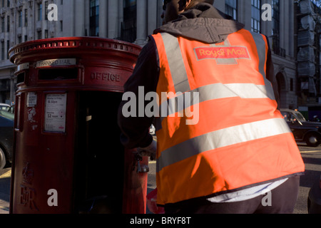 Un facteur de la Royal Mail fait une collecte planifiée de poster à partir d'une boîte postale à l'animation de la rue Piccadilly à Londres. Banque D'Images