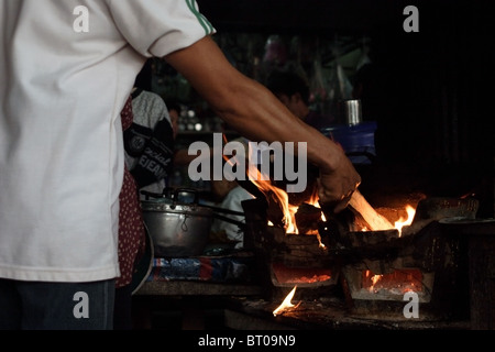 Un cuisinier prépare le petit déjeuner pour diners sur un poêle à bois dans un restaurant à Mae Hong Son, Thaïlande. Banque D'Images