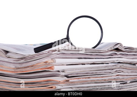 Agrandir verre au-dessus d'une pile de papier journal pour trouver des informations fraîches (isolé sur blanc) Banque D'Images