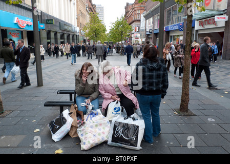 Les acheteurs de sexe féminin sur Sauchiehall Street assis fumer des cigarettes avec leurs sacs de shopping Glasgow Scotland UK Banque D'Images