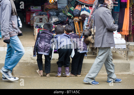 Trois garçons hmong noir curieux essayez de regarder la télévision dans la rue sous forme d'un magasin Banque D'Images