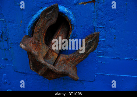 Old rusty anchor sur bleu foncé coque d'un bateau marchand en teck Banque D'Images