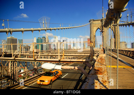 Jaune marque New York taxi cab sous les poutres en acier du pont de Brooklyn à Manhattan dans l'arrière-plan Banque D'Images