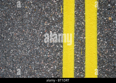 Deux lignes jaunes sont peintes sur revêtement bitumineux. L'autoroute est photographié de près. Il y a copie l'espace. Banque D'Images