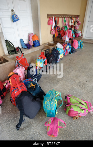 Mini-sacs et sacs à dos accroché sur des crochets et couché sur le sol à une école primaire Banque D'Images
