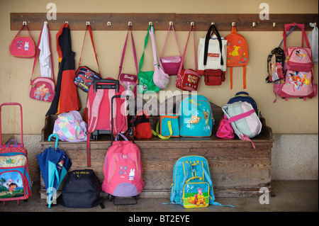 Mini-sacs et sacs à dos suspendu à des crochets et gisant sur le sol à l'extérieur d'une salle de classe dans une école primaire Banque D'Images