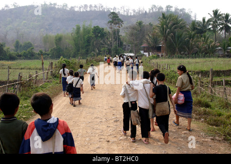 6 à 12 vieux fils les garçons et les filles sont à la maison sur un chemin de terre après une journée d'école élémentaire dans le Laos communiste. Banque D'Images