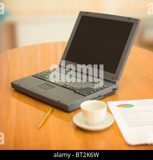 Ordinateur portable sur une table à l'office avec les documents et tasse Banque D'Images