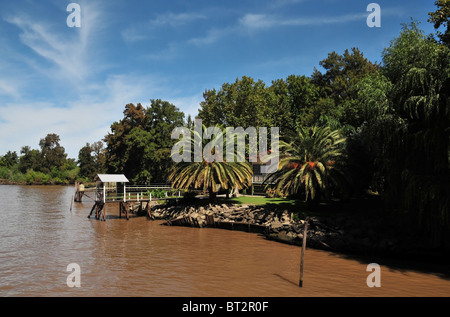 Vue oblique de la rive boisée, embarcadère, palmiers et holiday bungalow, Sarmiento, la rivière Parana Delta, Buenos Aires Banque D'Images