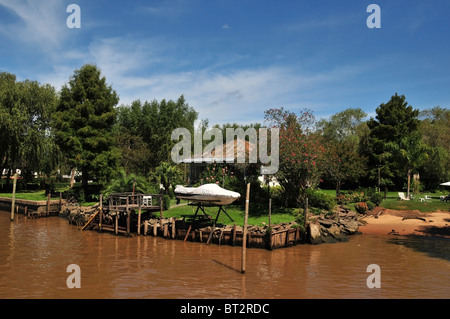 Bungalow avec jardin, rouge, d'herbe et de bush petit bateau suspendu au-dessus de la rivière, la rivière Parana Sarmiento, Delta, Buenos Aires Banque D'Images