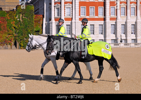 Horse Guards Parade Ground deux officiers de police métropolitains montés sur la baie d'équitation et chevaux gris vêtements de haute visibilité remarquables à Londres Angleterre Royaume-Uni Banque D'Images