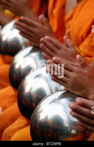 Les moines portant des robes orange prient avec leurs bols d'Aumône près de Tha Pae Gate dans Chiang Mai, Thaïlande. Banque D'Images