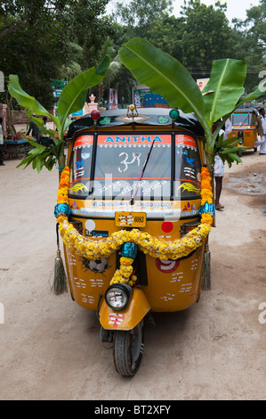 Rickshaw indien décorées de guirlandes de fleurs et de feuilles de bananier au cours de la fête hindoue du Dasara. Puttaparthi, Andhra Pradesh, Inde Banque D'Images