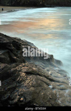 Surfez sur les roches de flou, personne qui marche sur la plage, Tresaith, Aberporth, Ceredigion, pays de Galles, Royaume-Uni Banque D'Images