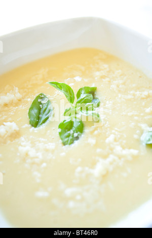 Soupe crémeuse aux asperges garnie de parmesan et de basilic frais dans un bol blanc carré Banque D'Images