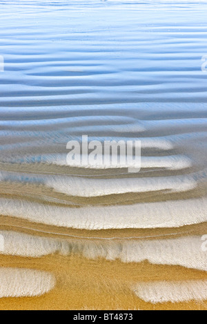 La texture du sable humide sur la rive de l'océan formé par vagues douces Banque D'Images