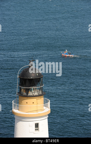 Un petit bateau de pêche au homard passe sous le phare de Douglas Head, à l'île de Man, au Royaume-Uni Banque D'Images