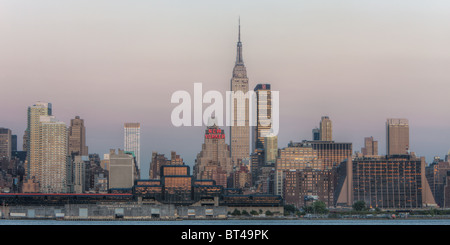 L'Empire State Building et Manhattan skyline au crépuscule avec la lueur orange du ciel de l'ouest reflètent dans les fenêtres de la ville de New York. Banque D'Images