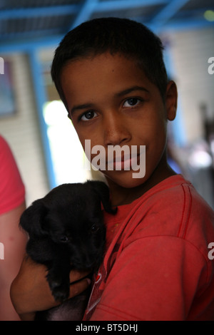 Portrait d'une jeune république dominicaine boy holding un chiot Banque D'Images