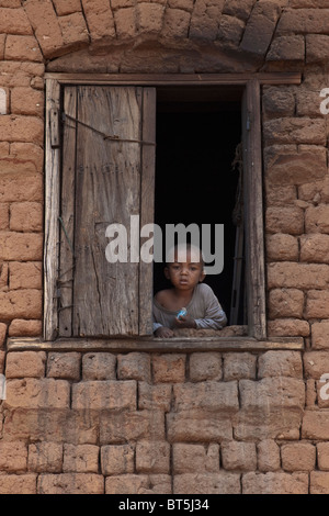 Jeune garçon à la fenêtre de sortie, Antananarivo, Madagascar. Banque D'Images