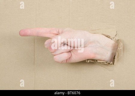 Mâle geste main à travers du trou dans le carton Banque D'Images