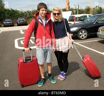 Teenage boy and girl twins avec valises rouge dans le parking de l'aéroport Banque D'Images