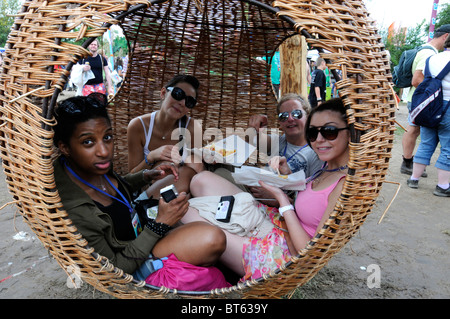 Panier en osier tissé chaise suspendue circulaire ronde globe fille filles déjeuner manger détendue au repos lunettes de soleil assis assis sourire happ Banque D'Images