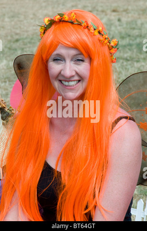 Glastonbury Festival 2010 festival des arts contemporains de l'orange rouge longue perruque de cheveux head sourire femme fille fleur Banque D'Images