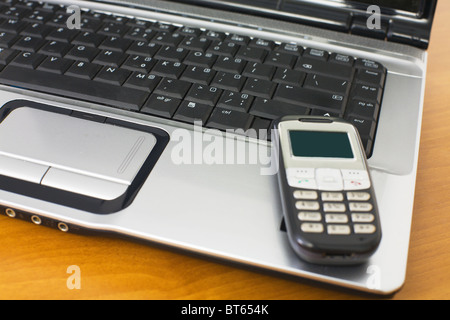 Téléphone mobile couché sur le clavier sur la table en bois Banque D'Images