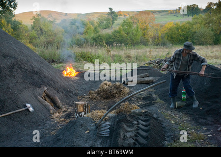 Nouveau allumé pile dans le charbon de bois traditionnel-brûleur's yard à Viscri village saxon, Transylvanie, Roumanie Banque D'Images