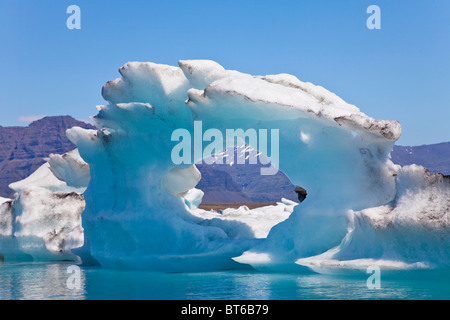 Un iceberg glaciaire avec un trou en son centre flottant sur la lagune Jokulsarlon, Iceberg, Islande Banque D'Images