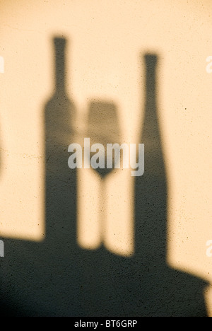Deux bouteilles de vin et un verre comme des ombres sur le mur. Banque D'Images
