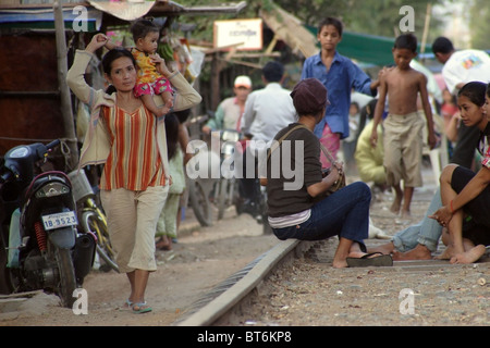 Une mère, son enfant est qu'elle marche aux côtés d'un tronçon de voie de chemin de fer abandonnée à Phnom Penh, Cambodge. Banque D'Images