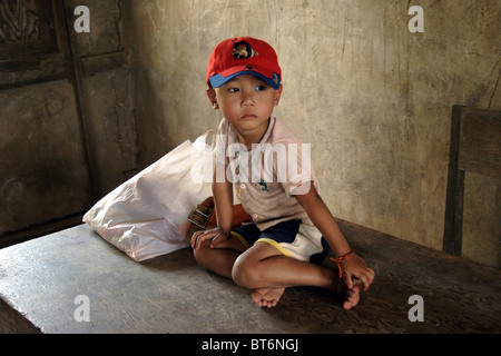 Un garçon asiatique de 4 ans est assis sur un bureau en bois de l'enseignant à l'école primaire de Parti communiste du Laos. Banque D'Images