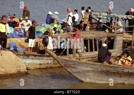 Un jeune garçon travailleur est de jeter une corde à un bateau qui arrive à un quai sur la rivière du Mékong à Stung Treng, au Cambodge. Banque D'Images