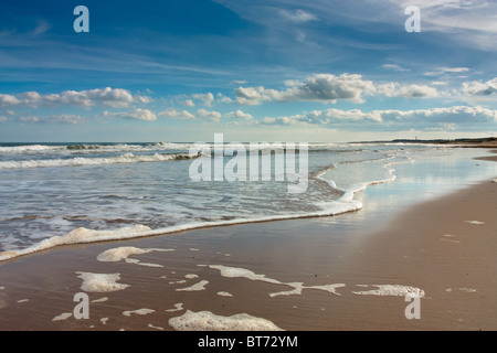 Sunny Beach avec ciel bleu, des nuages et des vagues déferlantes à Druridge bay la côte de Northumberland, Angleterre du Nord-Est. Banque D'Images