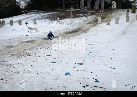Une fille en glissant sur une pente enneigée. Cimetière militaire de Netley, l'abbaye de Netley, Southampton, Hampshire. 10/01/10 Banque D'Images