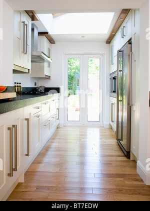 Parquet en bois poli dans cuisine moderne équipée avec portes patio et unités blanc Banque D'Images