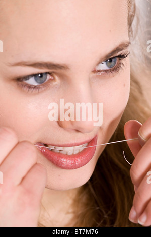 Jeune femme nettoyer ses dents avec du fil dentaire Banque D'Images