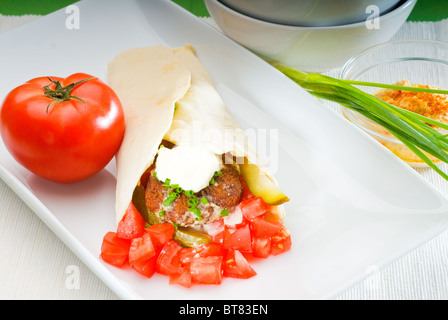 Falafel traditionnelle frais emballage sur le pain pita avec des tomates fraîches hachées Banque D'Images