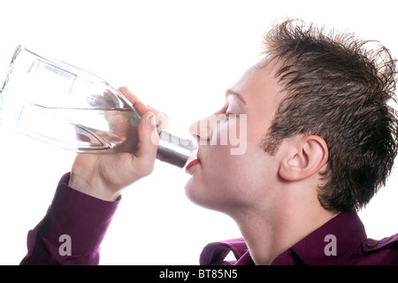 Le jeune homme boit une bouteille de vodka Banque D'Images