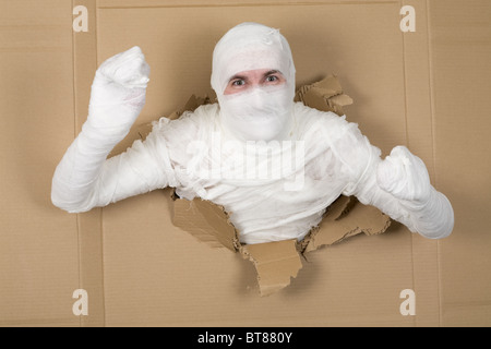 L'homme en costume à la momie à travers le trou dans le carton Banque D'Images