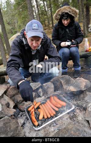 L'homme et la femme au barbecue saucisses en hiver, Stockholms Lan, Suède Banque D'Images
