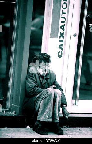 Vieil homme assis sur le trottoir devant Lisbonne Banque Banque D'Images