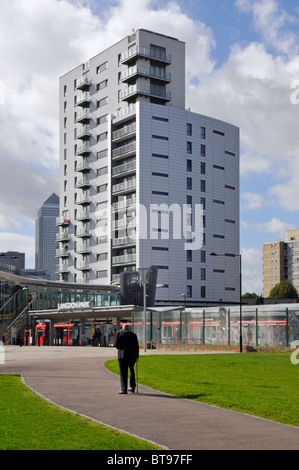 Seul homme avec bâton marche lentement vers Langdon Park Docklands Light Railway station de nouveaux immeubles de grande hauteur avec Canary Wharf au-delà Banque D'Images