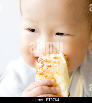 Un bébé asiatique de manger le pain Banque D'Images